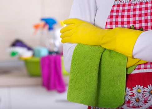 Cleaner working in a Putney flat kitchen during a routine visit